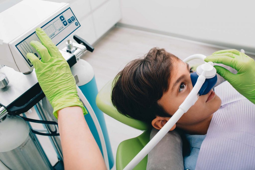 A patient receiving nitrous oxide sedation through a nasal hood in the dental chair